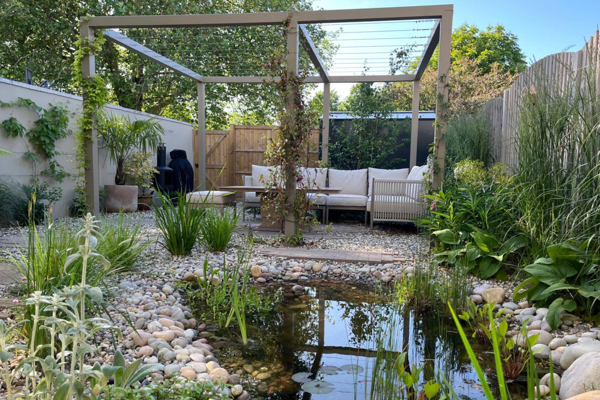 pergola with outdoor sofa alongside a wildlife pond