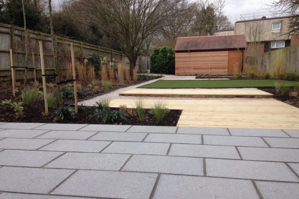 Landscaped garden of granite paving, a decking and limestone pathway, and western red cedar screen
