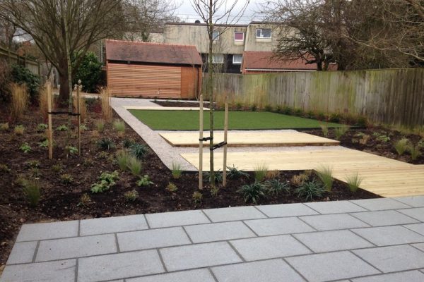 Contemporary garden with granite paving, decking and limestone gravel pathways and ornamental pear trees