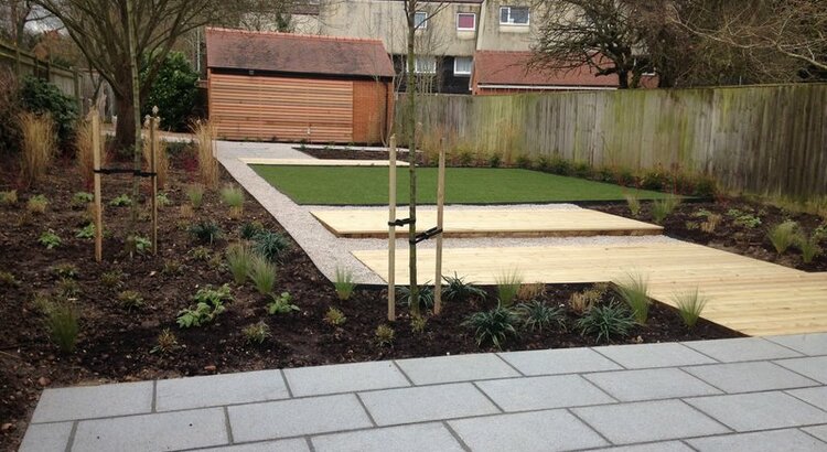 Contemporary garden with granite paving, decking and limestone gravel pathways and ornamental pear trees