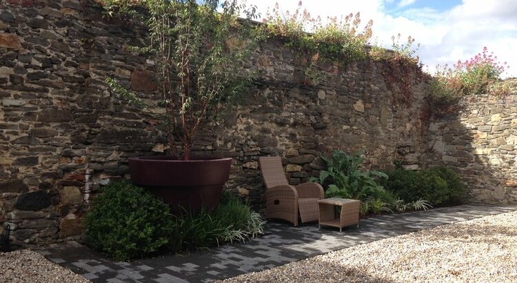 Walled garden featuring oversized planter and cherry tree